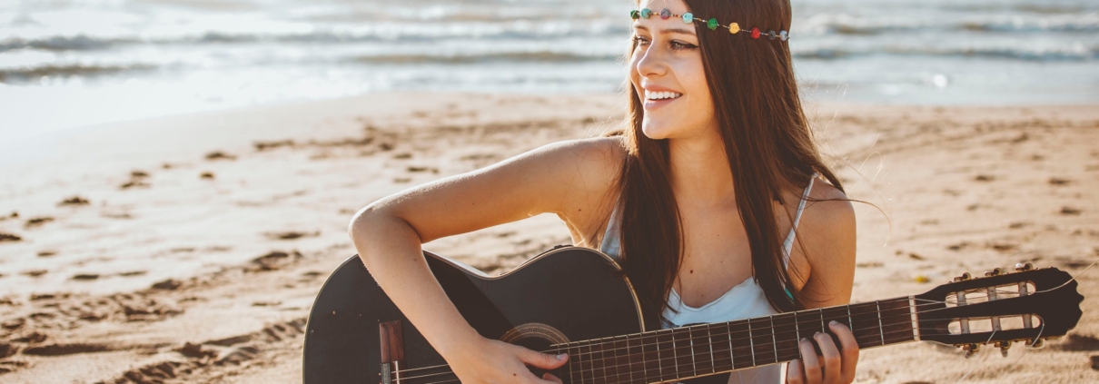 smiling hippie girl playing guitar