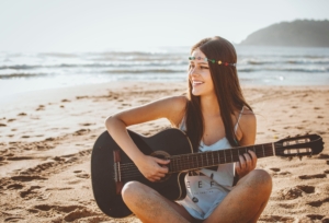 smiling hippie girl playing guitar