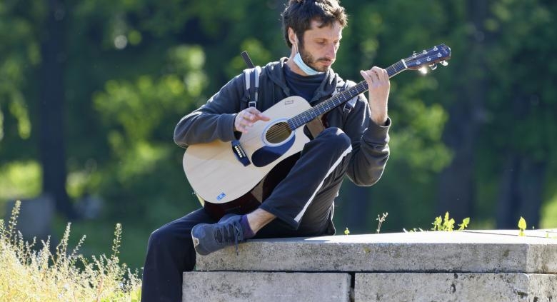 Strumming guitar in nature on stone bench